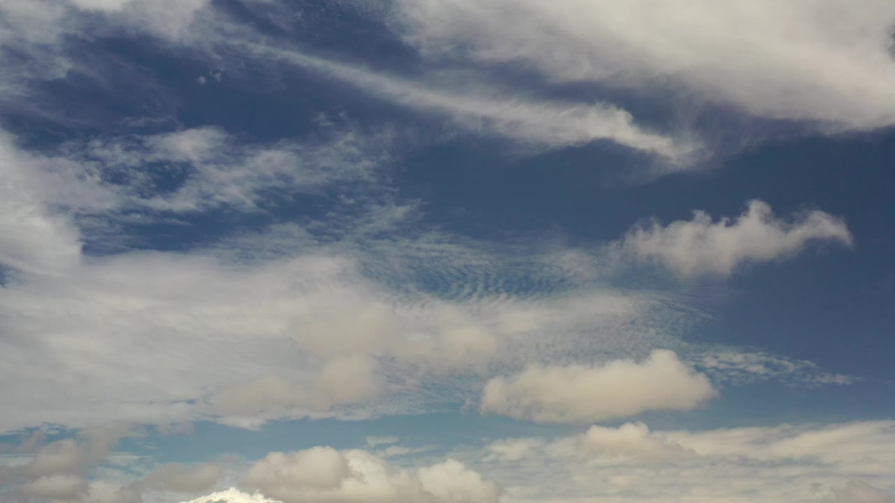 Los Cabos sky view with darker blue upper sky, wispy cloud streaks, and a small bright cloud cluster near the lower area, with no visible people.