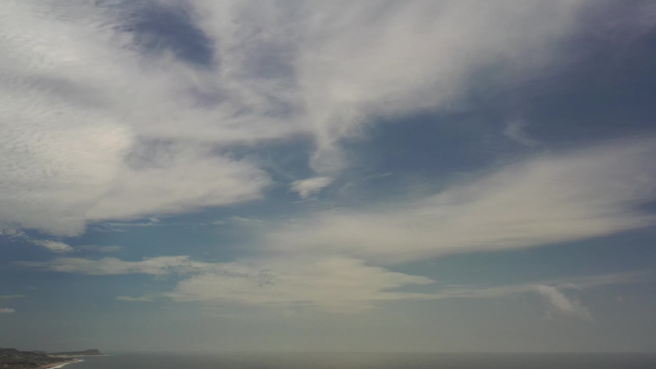 Layered clouds and blue sky above distant water