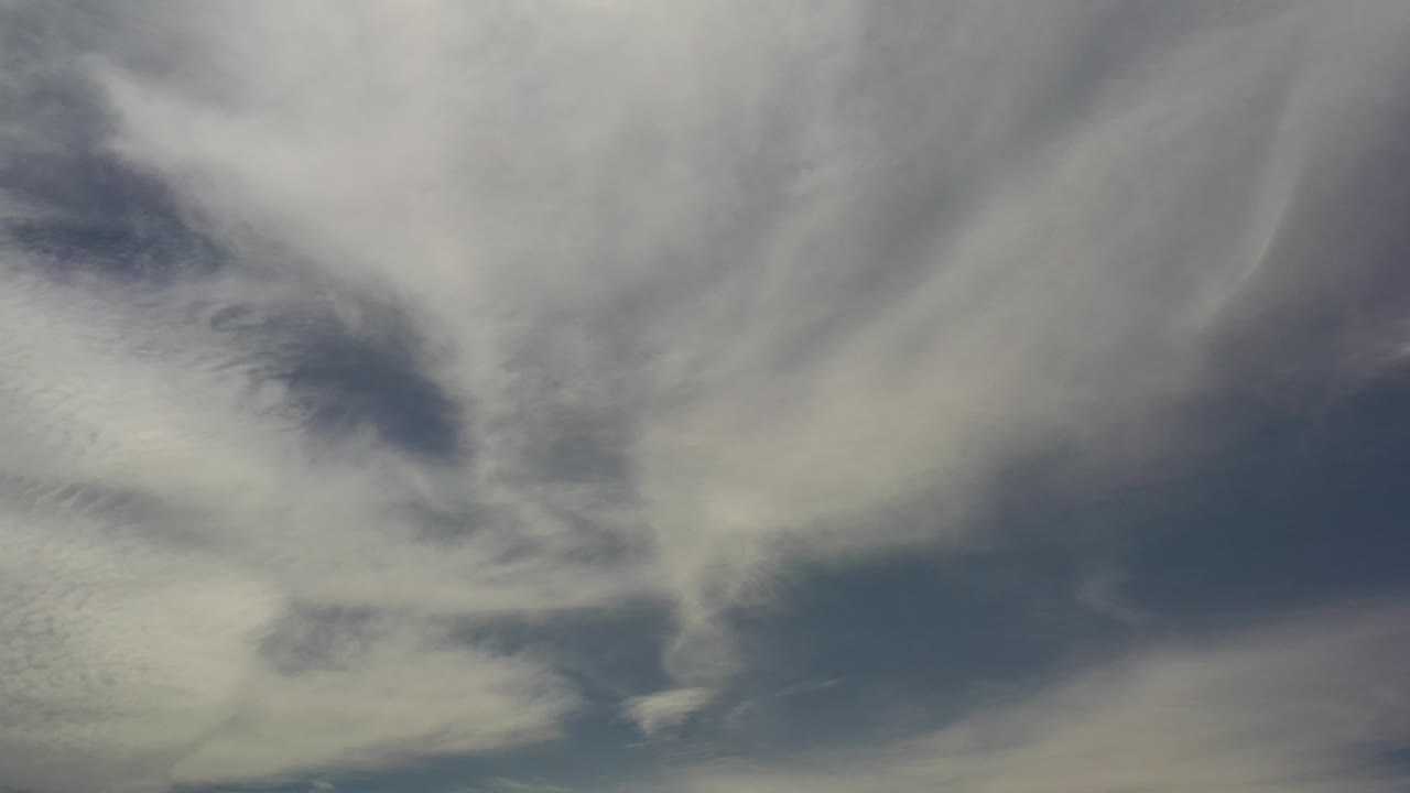Broad white cloud streaks over blue-gray sky