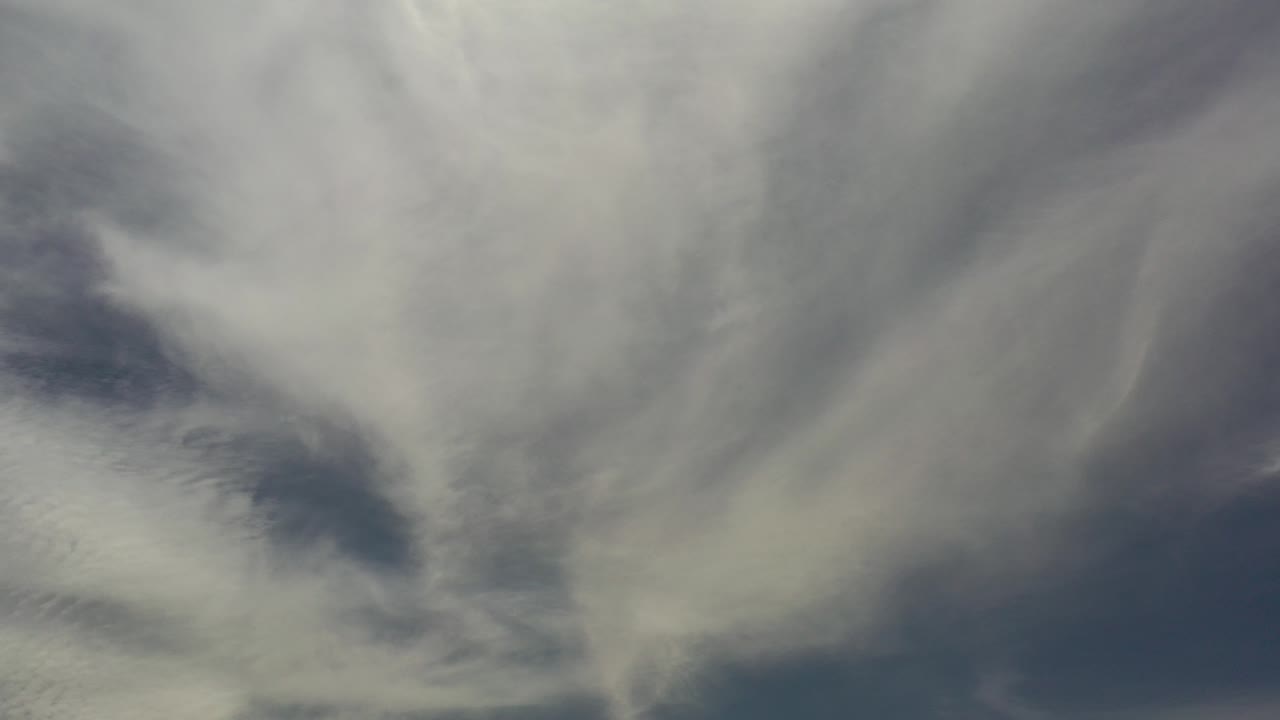 Soft white and gray clouds spread across a muted blue sky over Los Cabos, Mexico, with no visible people or built structures.