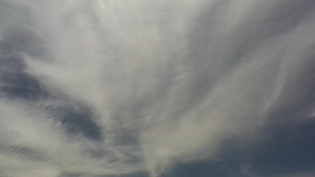 Layered cotton-like cloud forms fill most of the Los Cabos sky, leaving darker blue openings near the lower edge and no visible people.