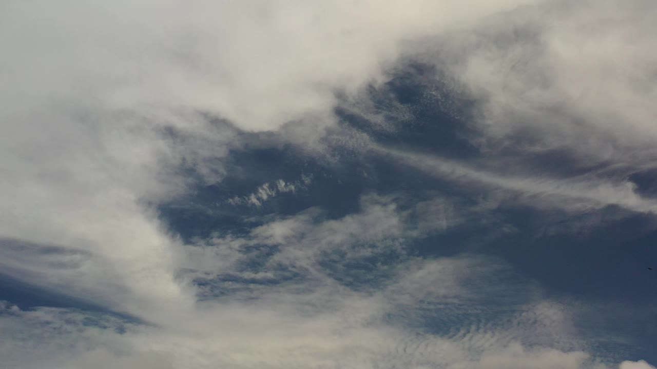 Los Cabos sky view with a broad white cloud band across the upper left, darker blue opening near center, and no visible people.