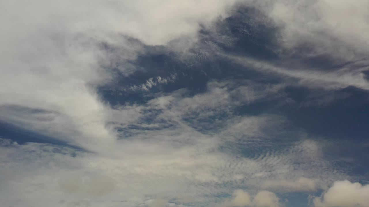 Los Cabos sky with a darker blue opening near the upper center and pale cloud bands across the frame, with no visible people.