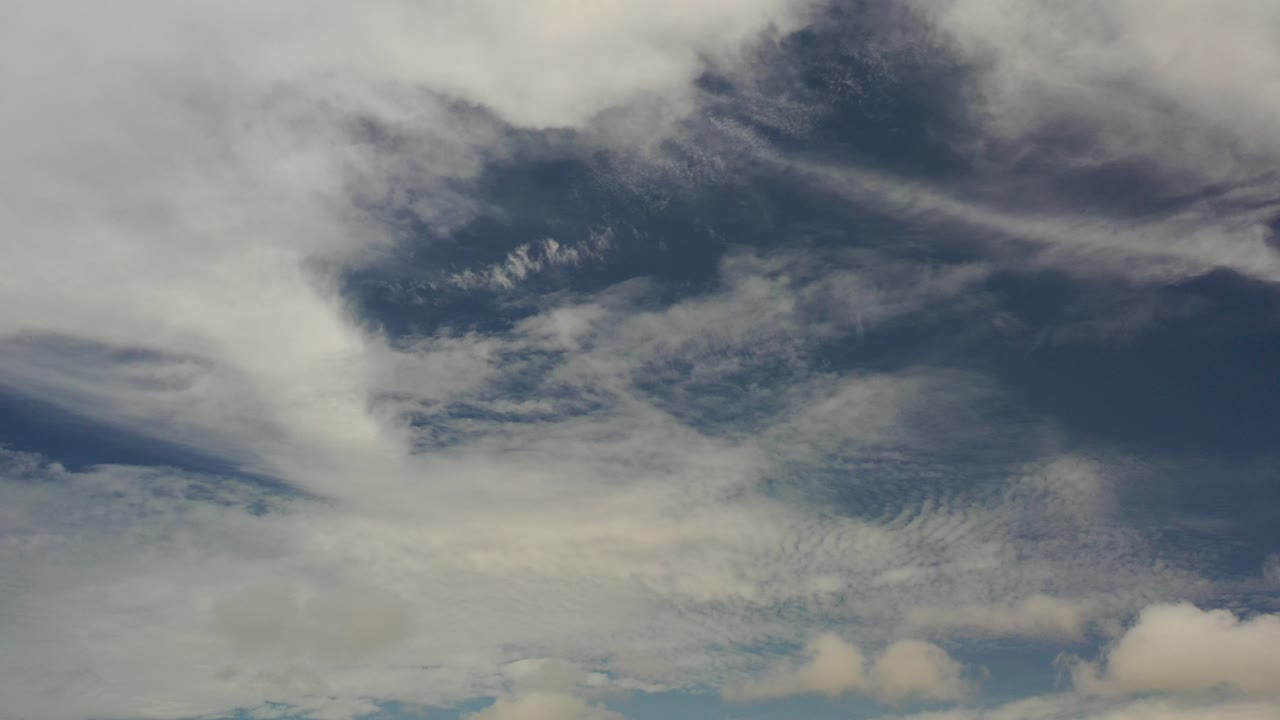 Opening frame of layered white and gray clouds over blue sky in Los Cabos, Mexico, with no visible people.