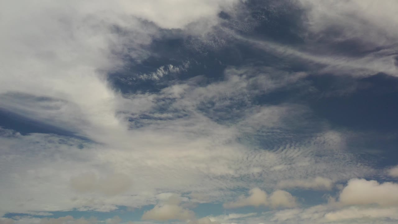 White cloud sheet and darker clouds against blue sky.