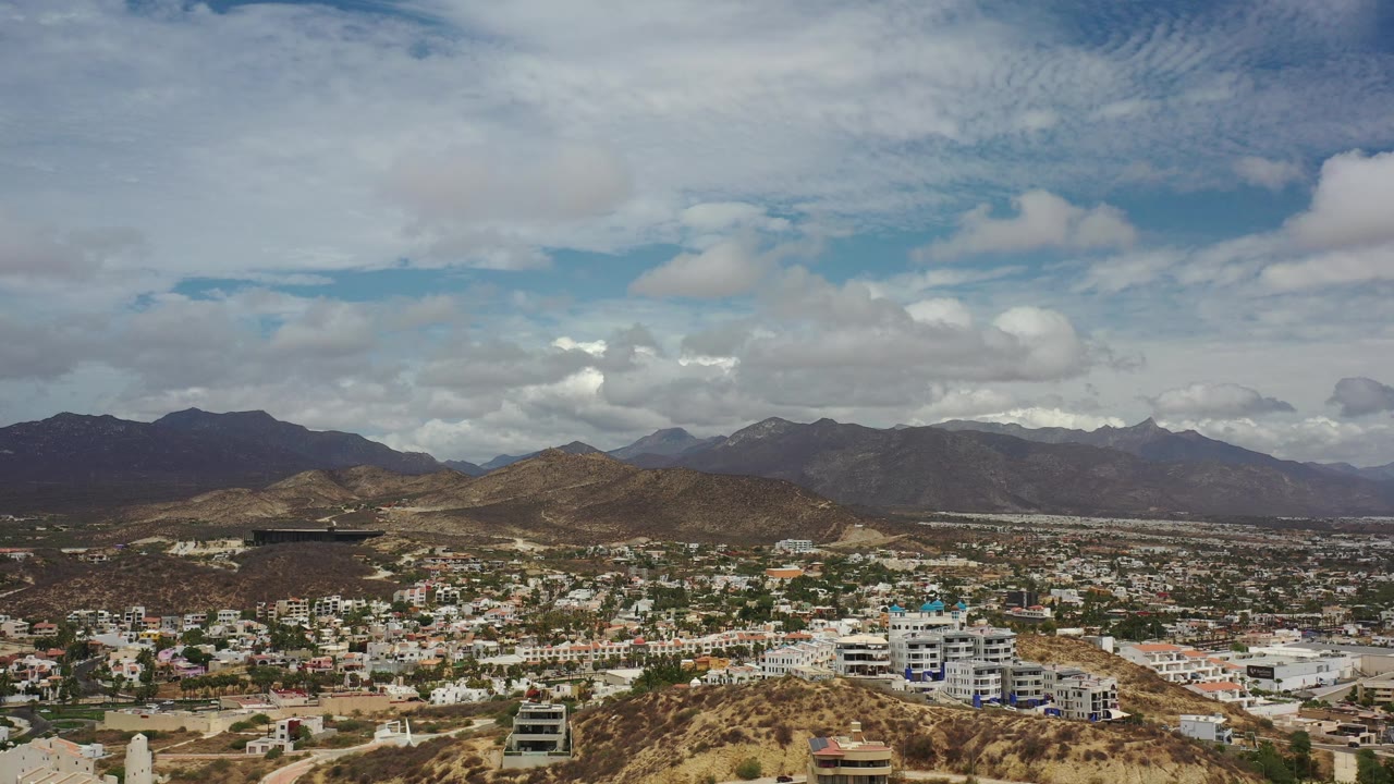 Desert urban area with mountains and thick clouds seen from above.