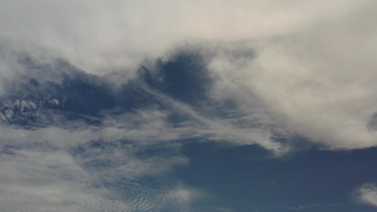 Aerial view in Los Cabos, Mexico, with pale clouds covering much of the frame above dark blue water and no visible people.