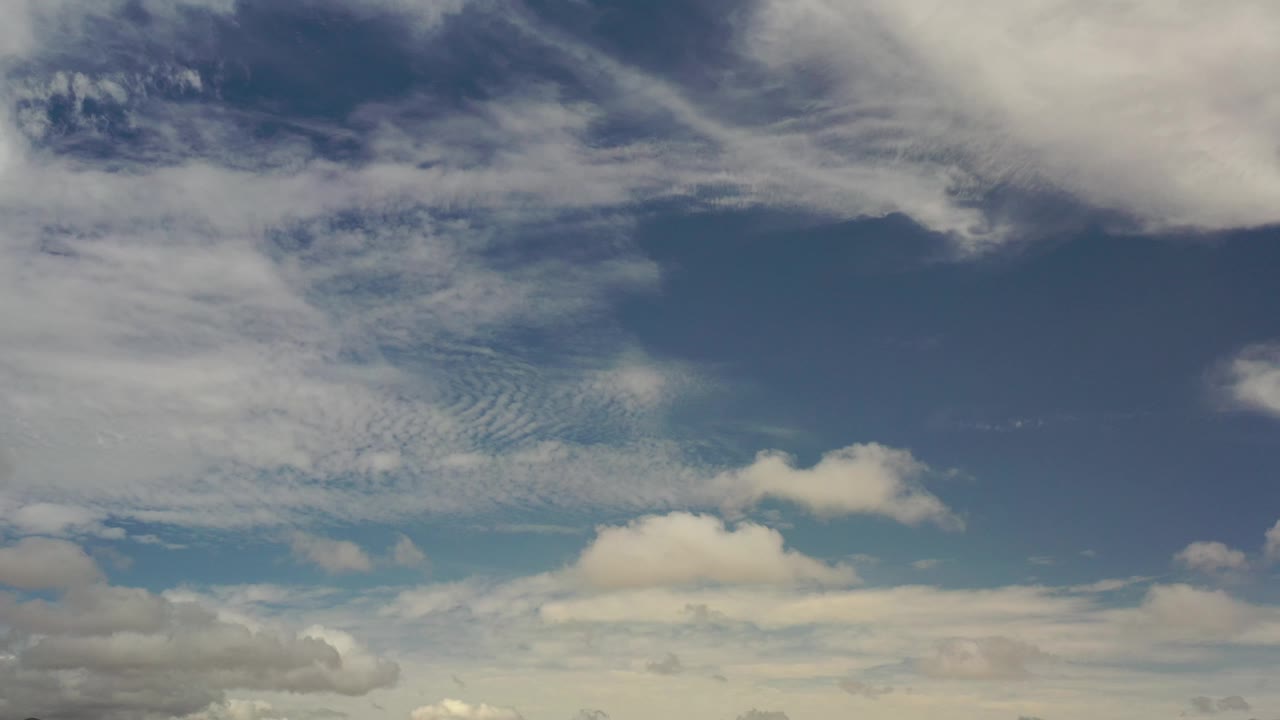 Scattered clouds over blue sky with a pale lower horizon.