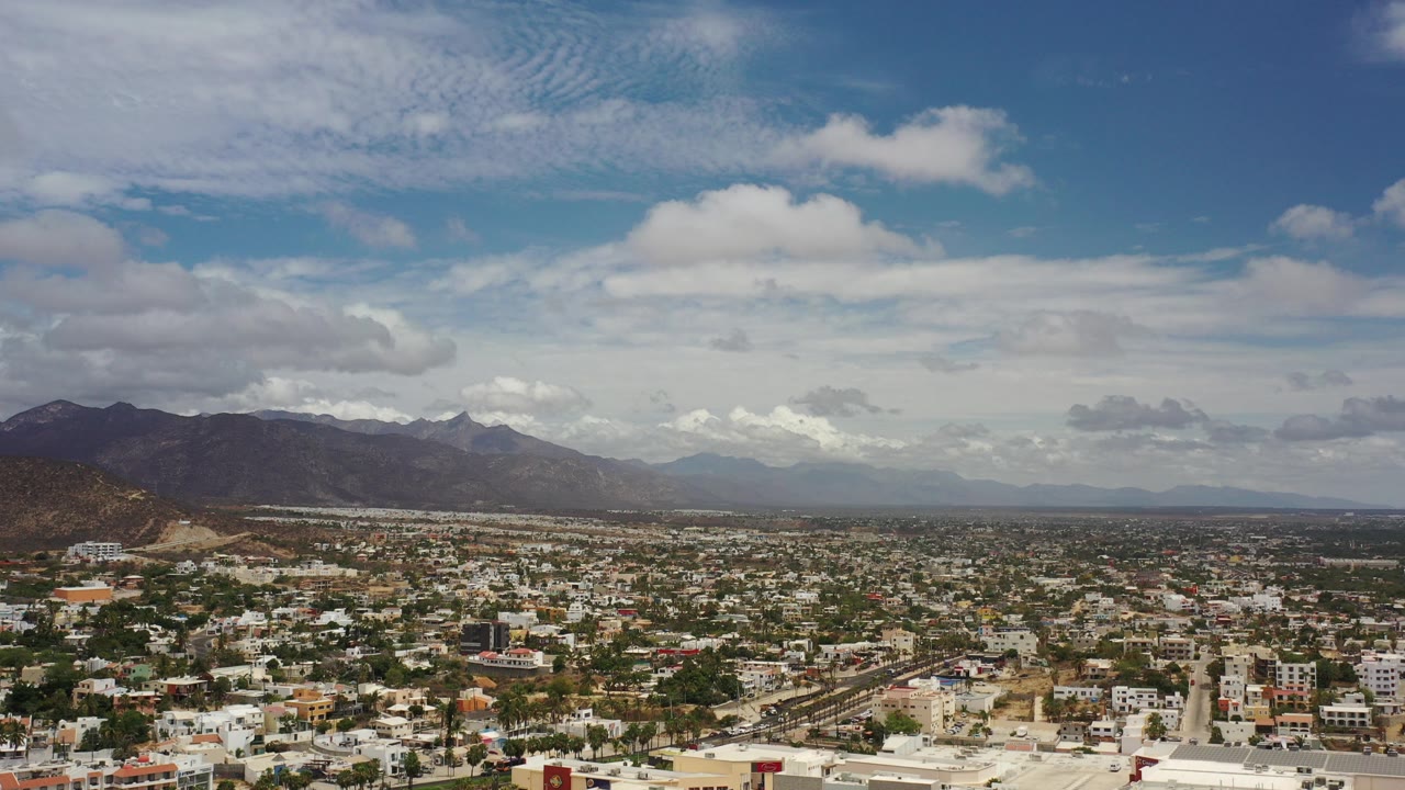 Elevated town view with mountains and clouded blue sky.