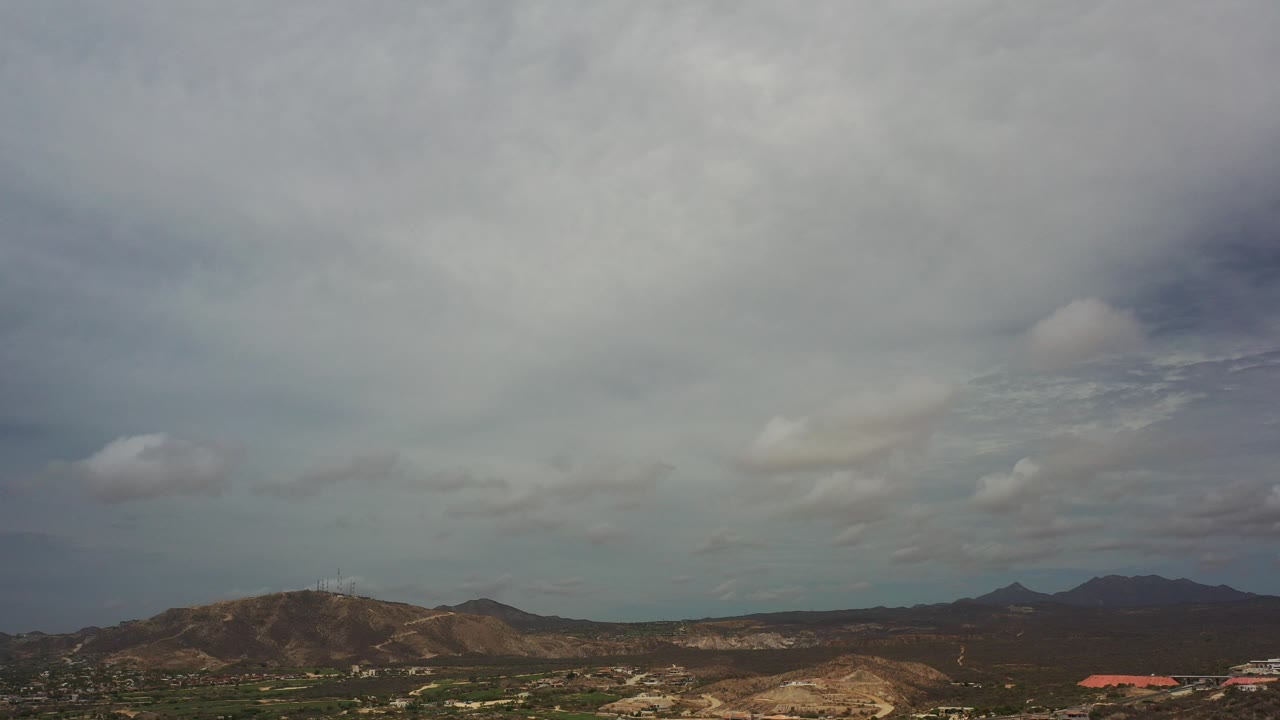 Wide mountain ridges beneath a large cloudy sky.