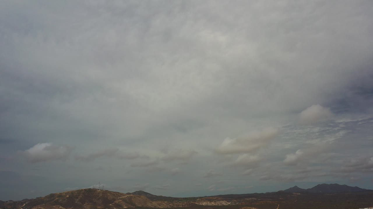 Wide view of cloudy skies over rocky mountains in Los Cabos, Mexico, with muted light and no visible people.