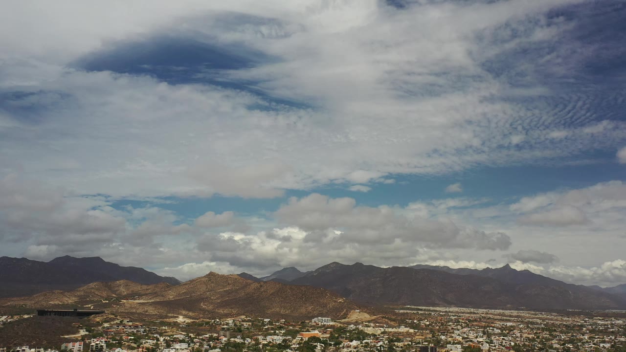 Los Cabos mountain ranges stretch across the frame with scattered settlement along the lower edge and no visible people.