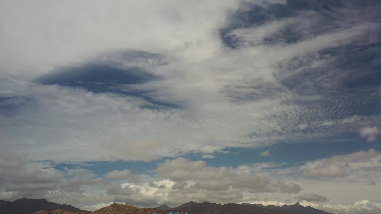 Wide cloudy sky over distant mountains and low terrain.