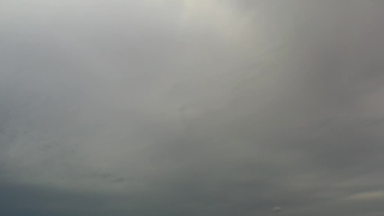 Soft layered clouds spread across the Los Cabos sky, with a darker blue-gray band near the lower edge and no visible people.