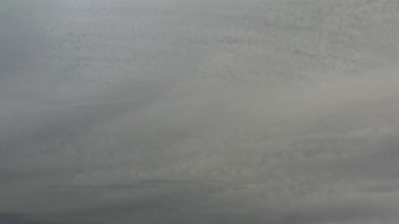 A dense section of gray cloud cover fills the Los Cabos frame, with softer white patches and no visible people.