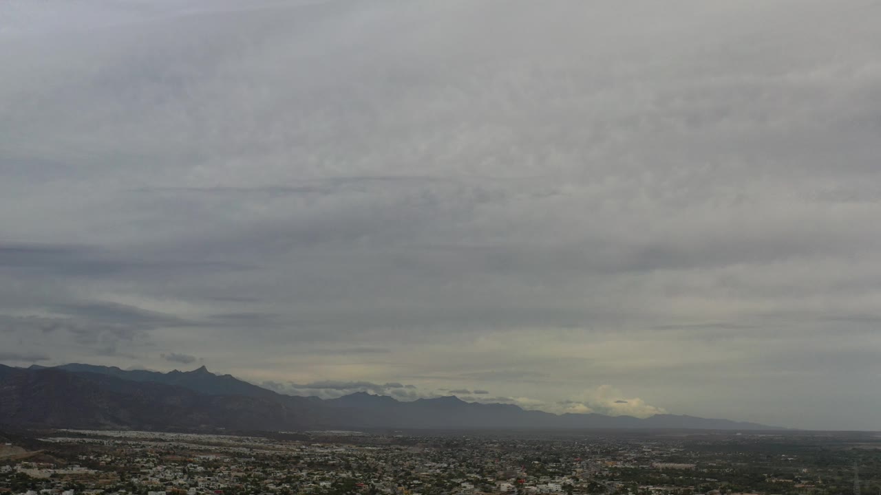 City and mountain panorama with cloudy sky filling most of the frame.