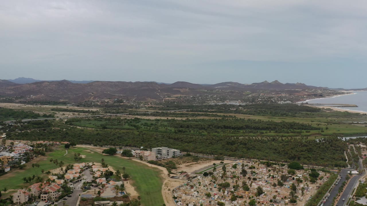 Aerial view over green land, homes, hills, and a bay