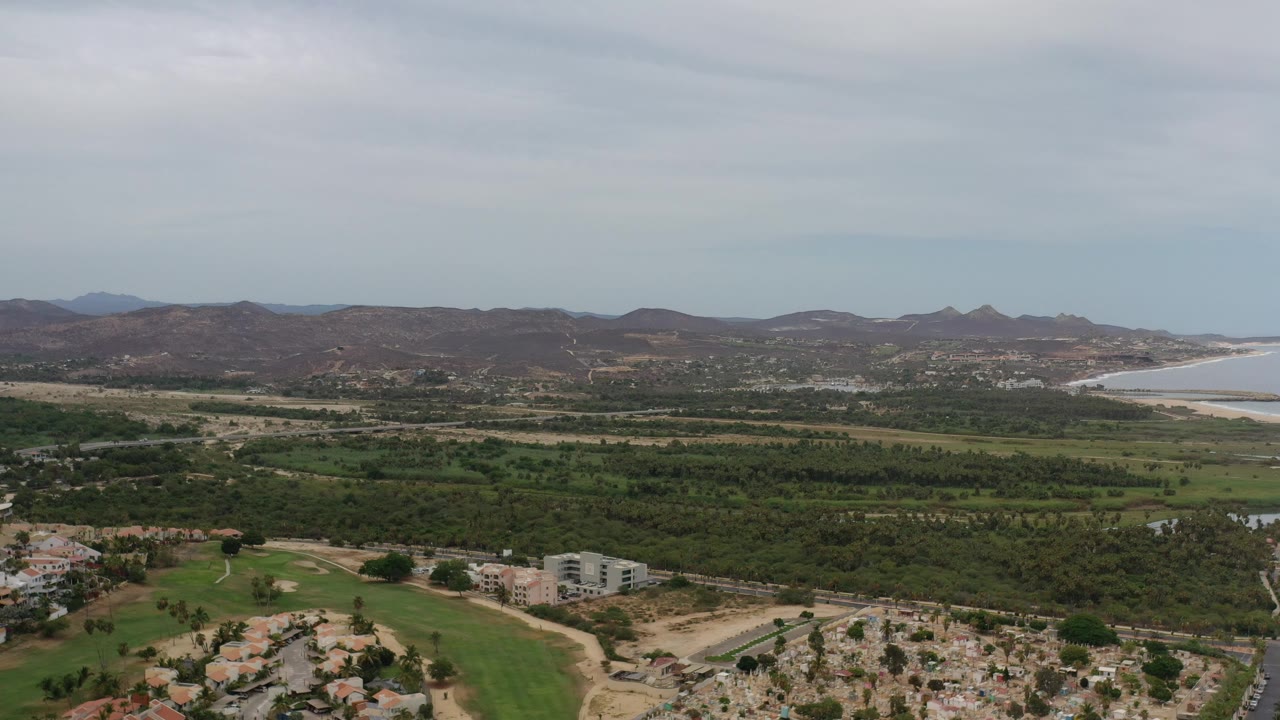 Overcast aerial view of hills, valley vegetation, and distant water.