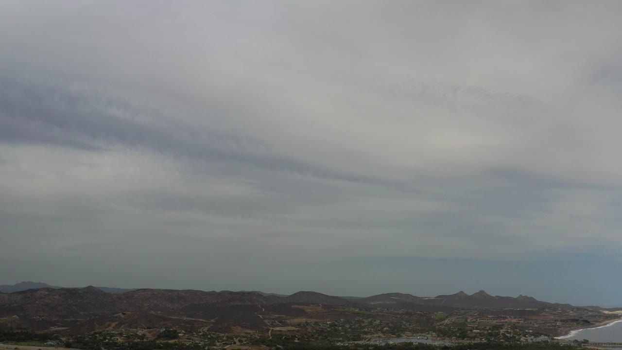 Cloudy sky over distant hills and coastline.