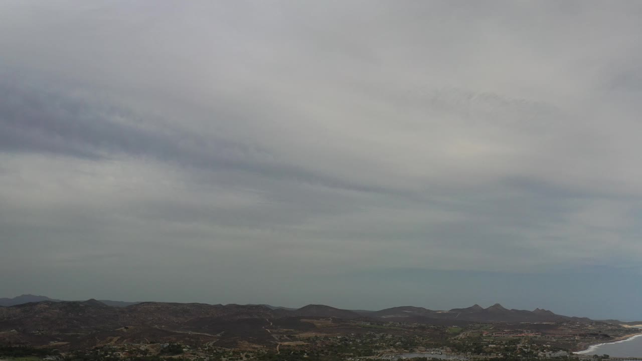 Gray clouds over coastal hills and surf.