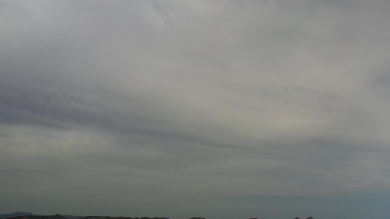 Gray-white cloud cover fills the first Los Cabos frame, with a dark low horizon and no visible people.