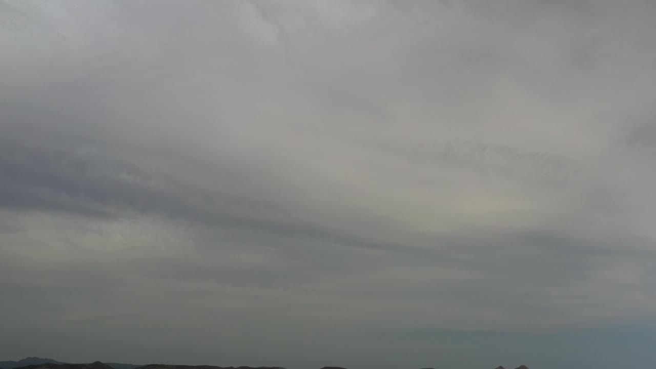 Soft gray clouds above a low dark shoreline silhouette.