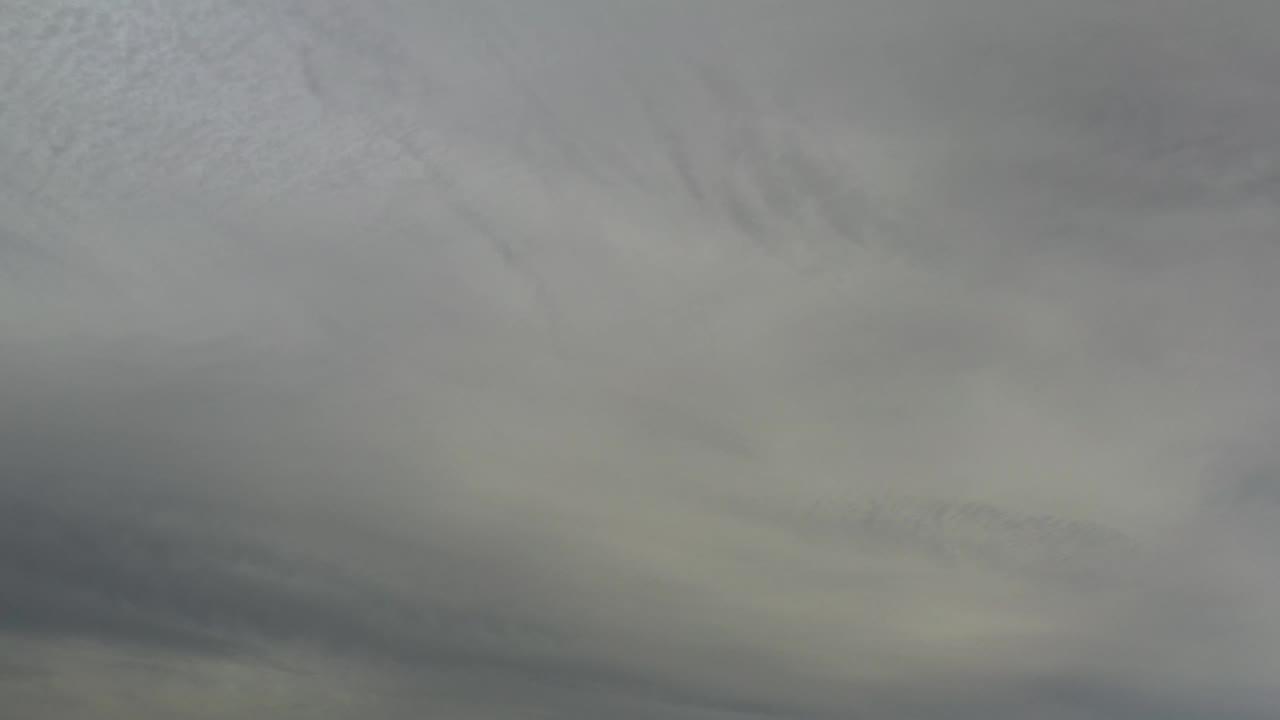 Soft gray cloud bands spread across a pale Los Cabos sky, with the frame remaining abstract and no visible people.