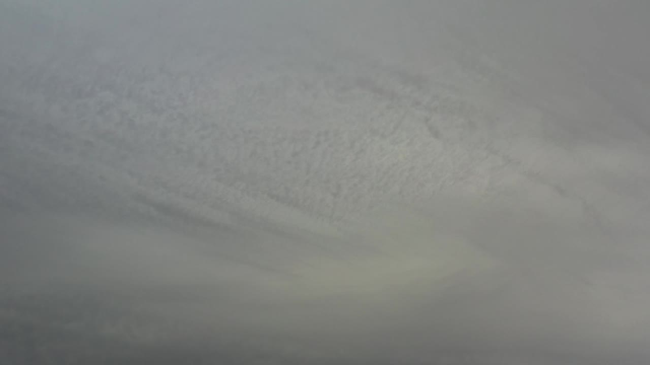 A soft overcast sky over Los Cabos, Mexico shows pale gray cloud texture across the upper frame and a heavier dark band below, with no visible people.