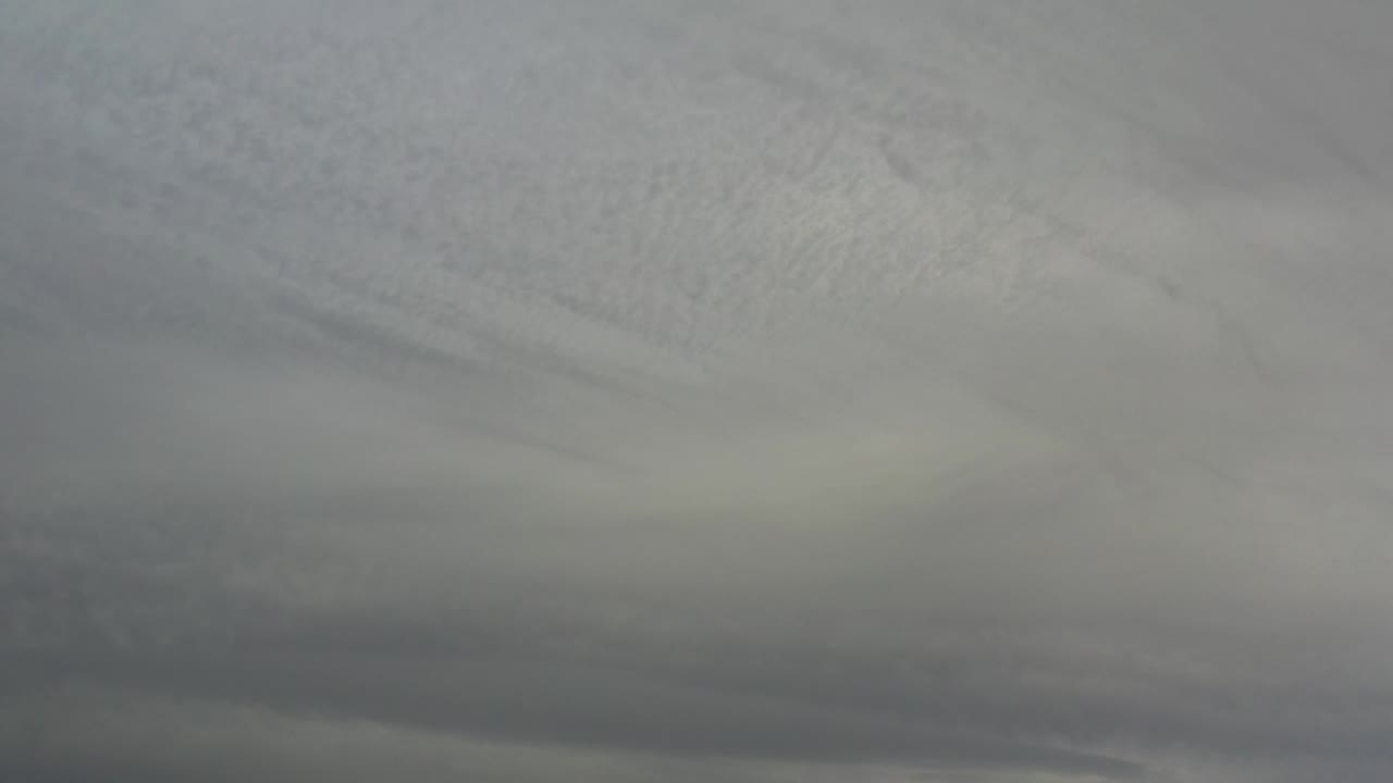 A broad overcast cloud layer stretches across the Los Cabos sky, with soft gray tones and no visible people.
