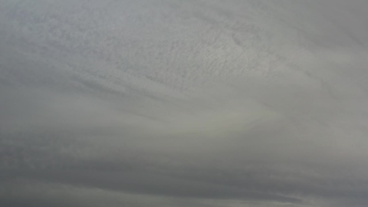 Dark horizontal cloud band below pale gray clouds.