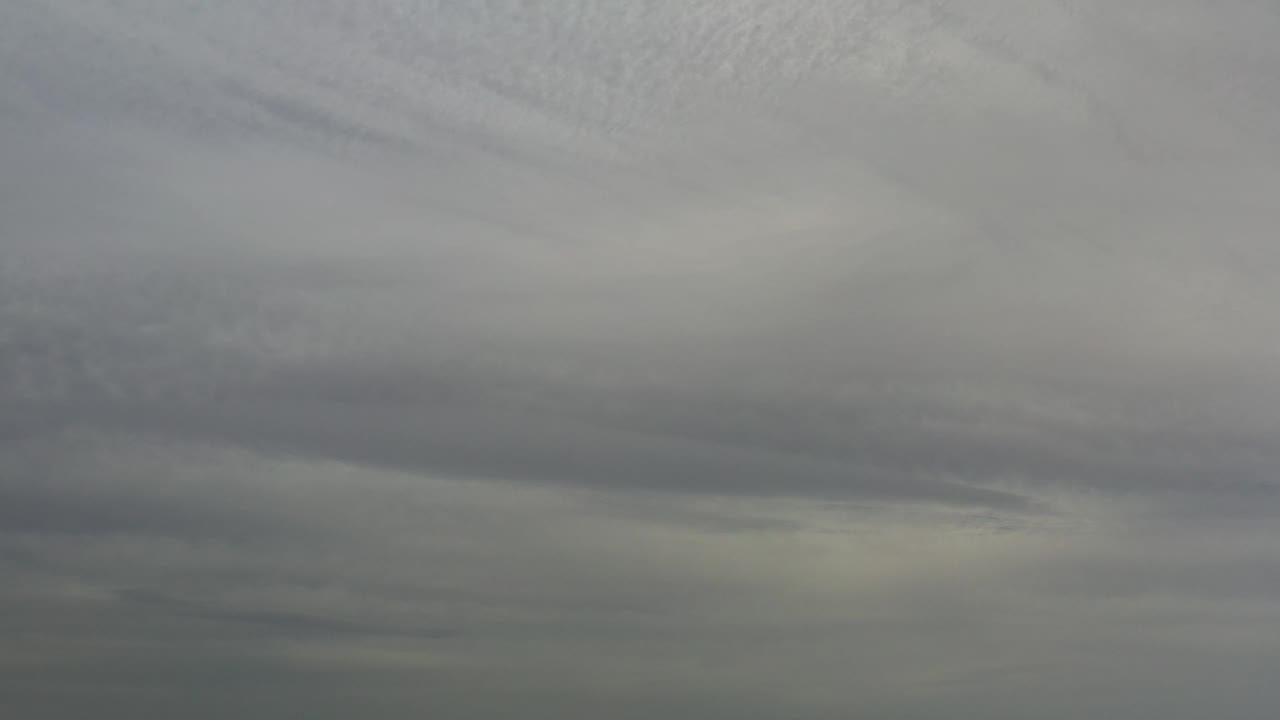 Layered overcast sky fills the frame while faint hills sit along the bottom edge in Los Cabos, with no visible people.
