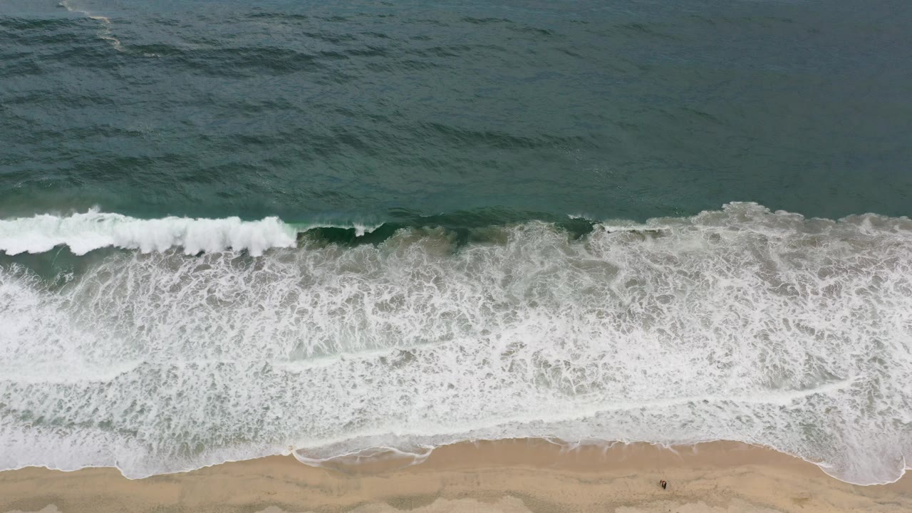 Overhead surf breaking onto a sandy beach
