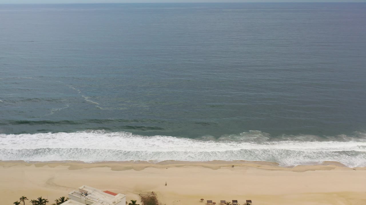 Aerial view of ocean waves breaking onto a sandy beach.
