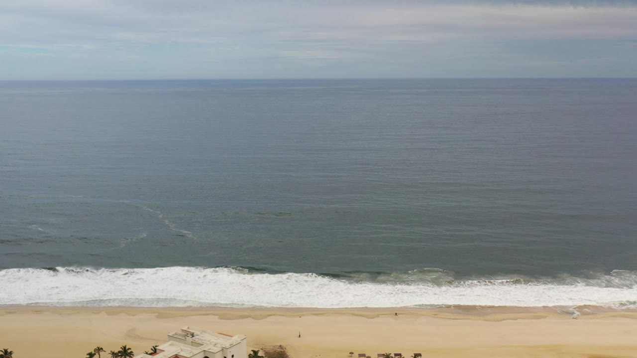 Wide cloudy ocean above a narrow sandy beach