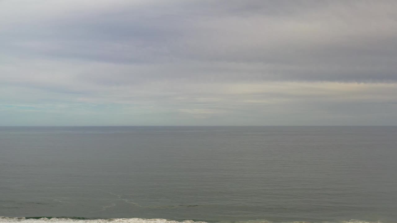 Los Cabos sea surface sits under a heavy overcast sky, with muted green-gray water and no visible people in the frame.