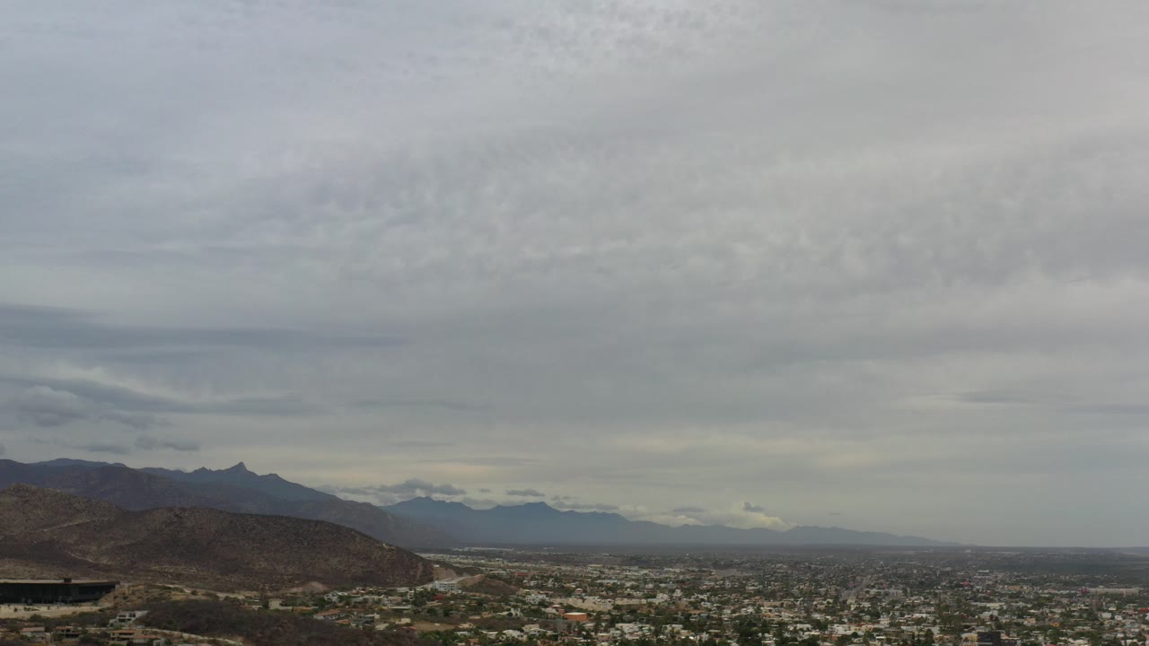 Wide view of cloudy sky over city and mountains