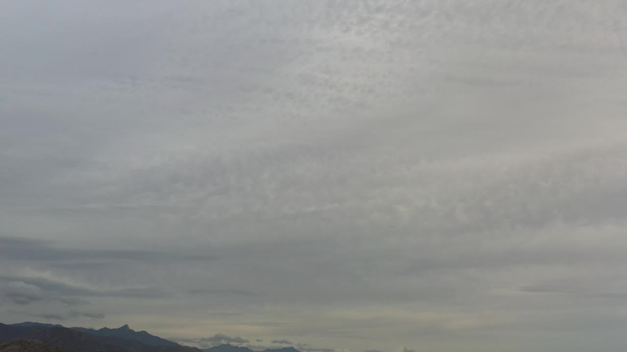 Layered gray clouds over a thin mountain horizon.