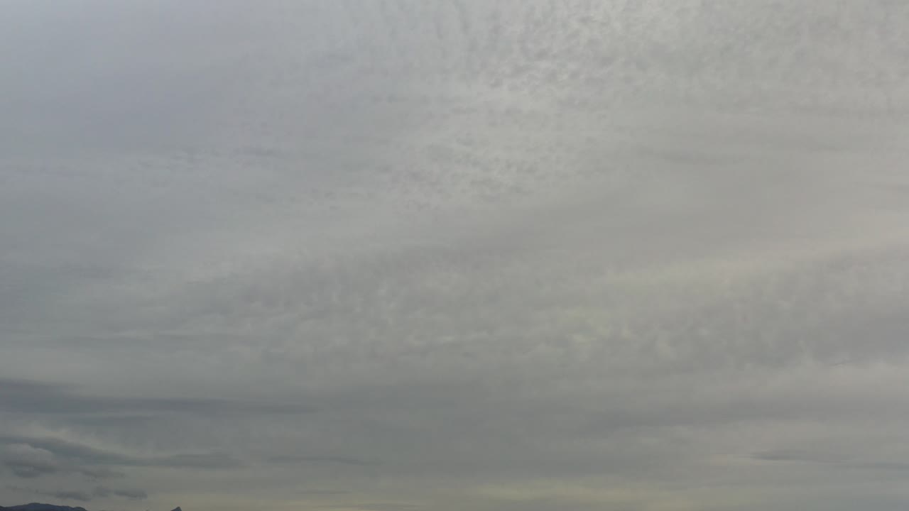Gray and white cloud cover fills the Los Cabos sky at the start of the clip, with a narrow dark horizon strip along the bottom and no visible people.
