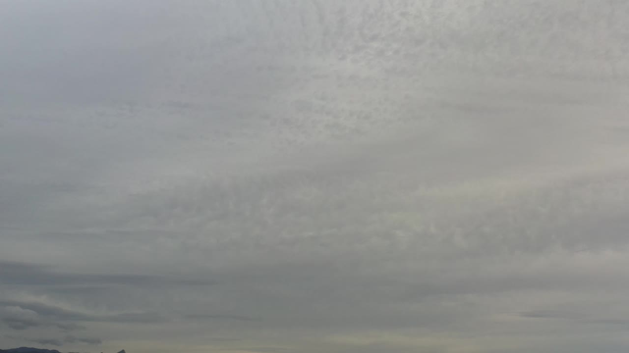 Layered gray and white clouds over low dark land