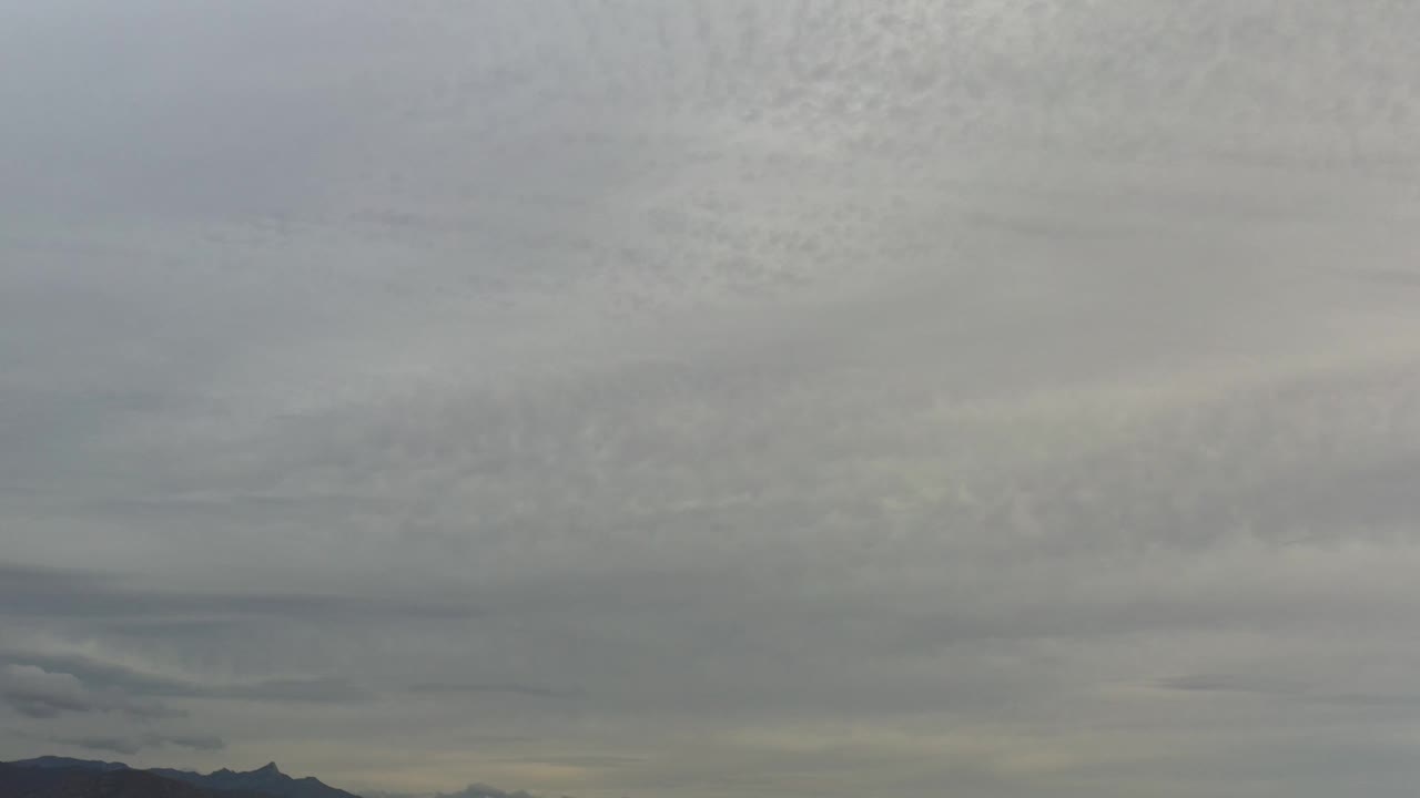 A dense overcast sky fills the frame above dark distant ridges in Los Cabos, Mexico, with no visible people.