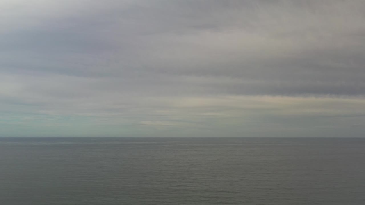 Muted ocean surface beneath a heavy cloud layer.
