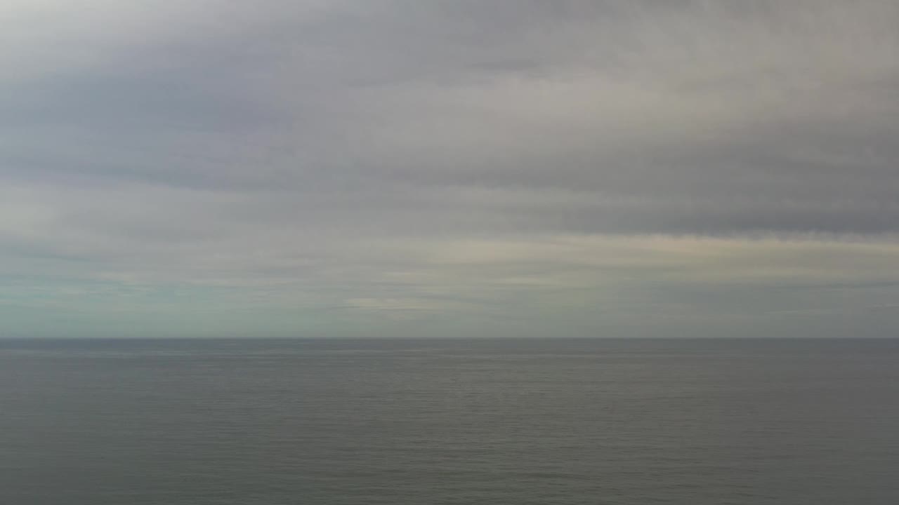 Los Cabos ocean water sits below a low, darker cloud band, with the horizon centered and no visible people.