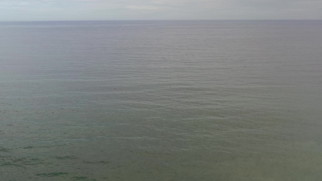 Open Los Cabos ocean view with faint darker patches below the surface, a soft sky band above the horizon, and no visible people.