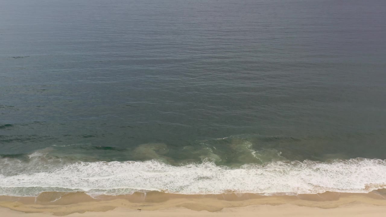 Overhead ocean and surf with beach along the lower edge.