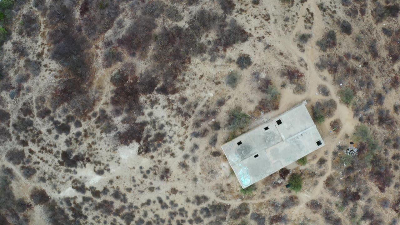 Concrete building at the upper right of an overhead desert view.