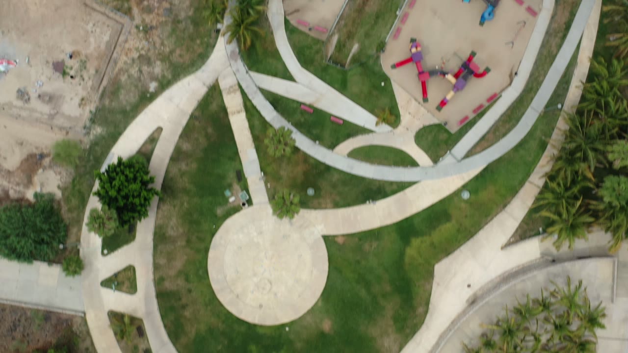 Overhead view of curved paths, lawns, palms, and a small play area.