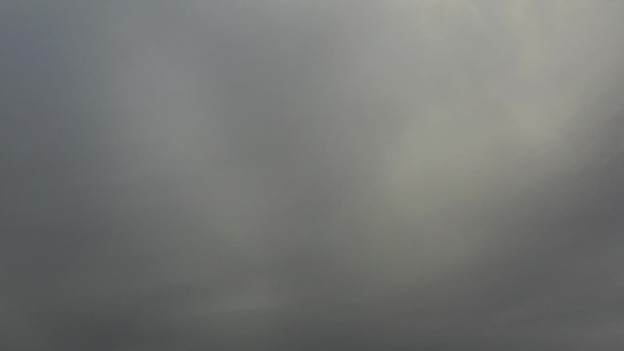 Soft gray storm cloud cover fills the frame in Los Cabos, Mexico, with a pale patch of brightness near the upper right and no visible people.