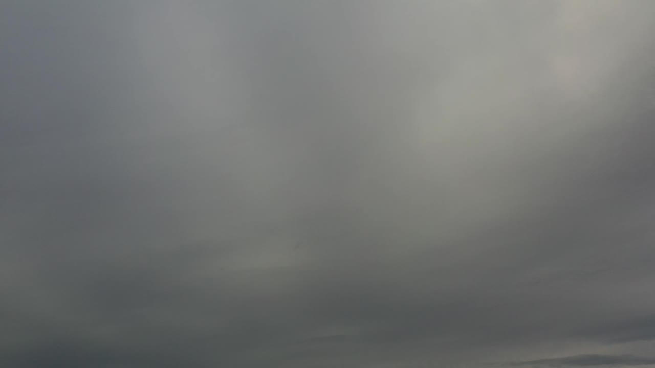 Los Cabos sky view with soft gray cloud bands and a thin distant horizon remaining low in the frame, with no visible people.