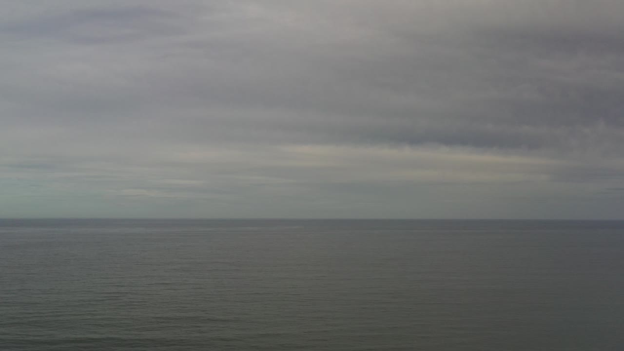 Los Cabos ocean horizon under layered gray cloud cover at the start of the clip, with dark muted water and no visible people.