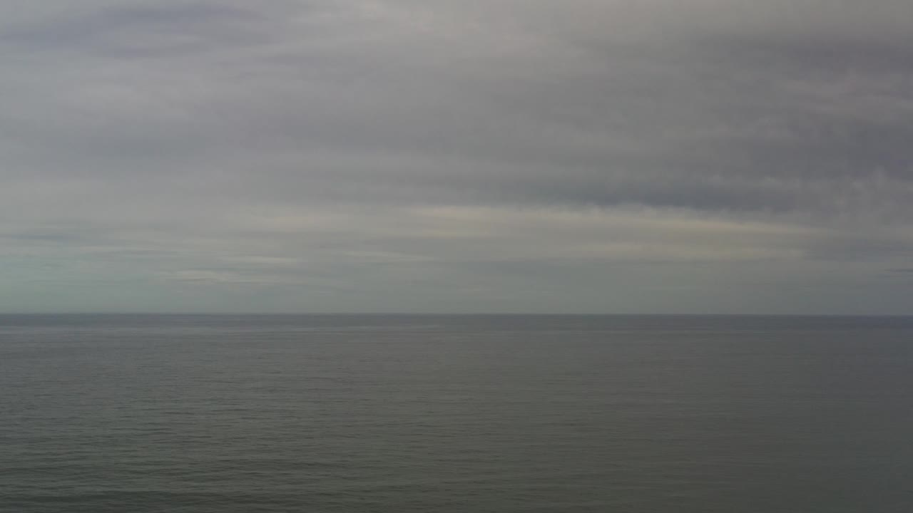 Muted ocean surface below a banded gray sky.